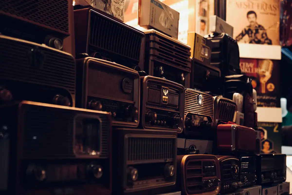 Aparate de radio vechi, așezate în stive, amintind de comunicatele epocii
