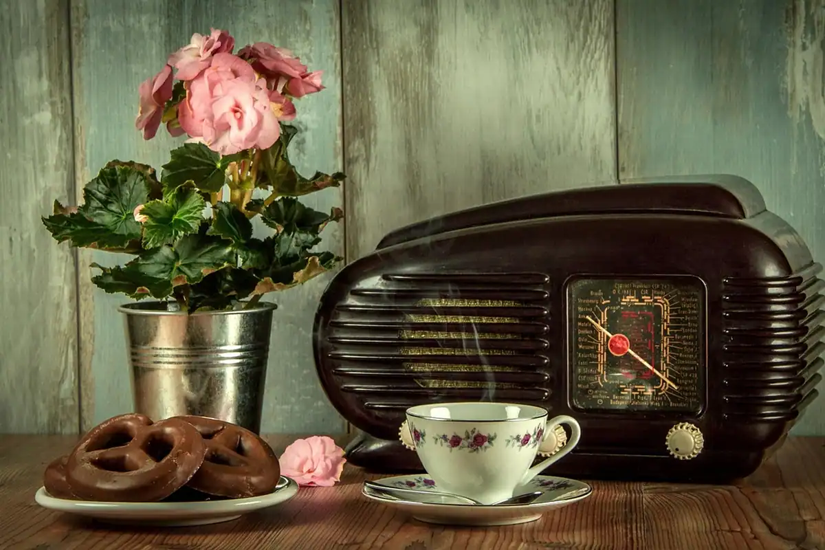 Aparat de radio vechi, în stil retro, așezat pe o masă lângă o ceașcă de cafea