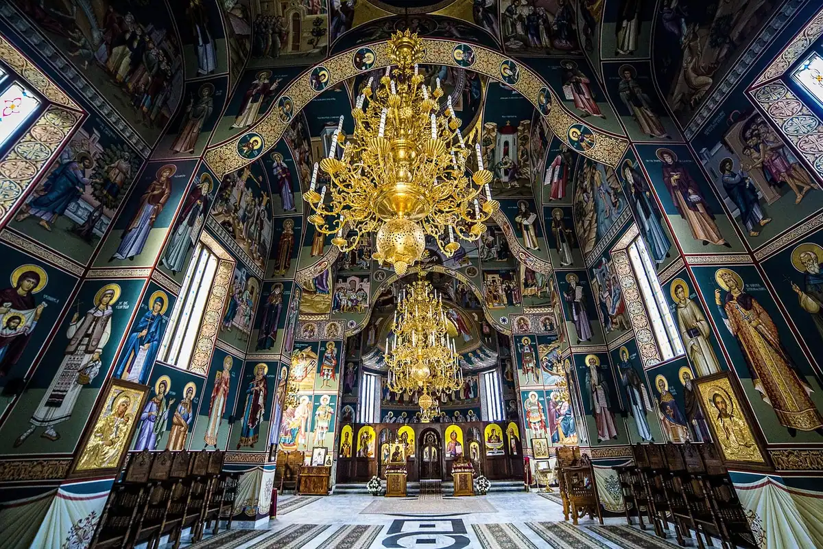 Interior de biserică din Bucovina cu fresce, icoane și un candelabru auriu