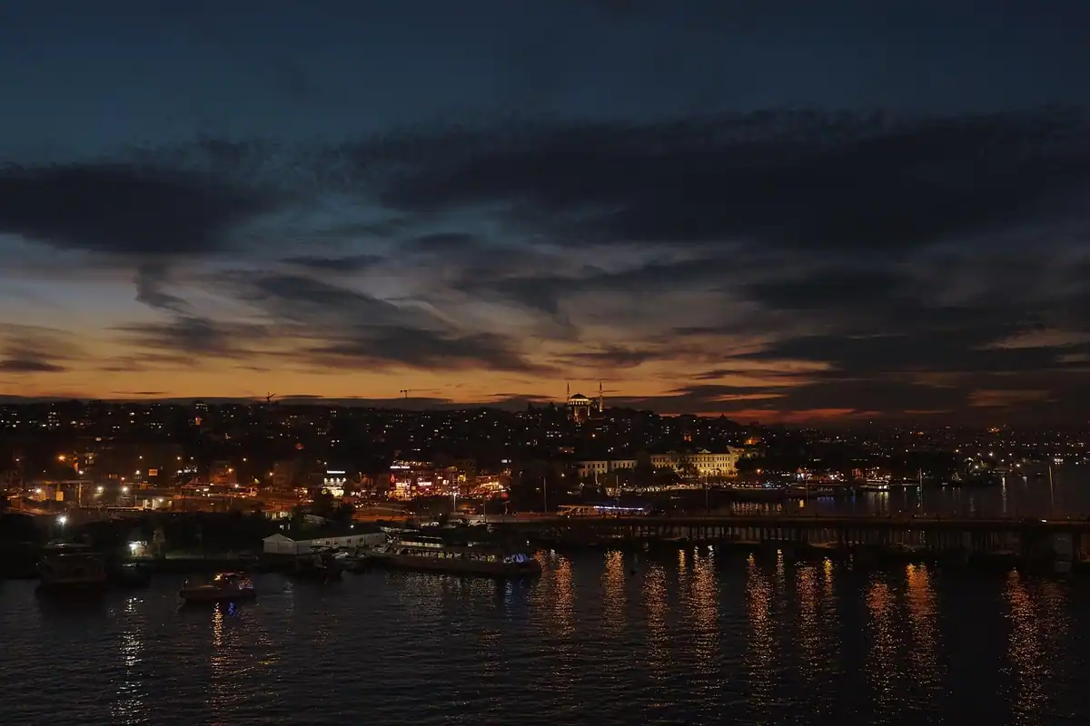 Orașul văzut de la malul mării, cu clădiri luminate noaptea lângă apă