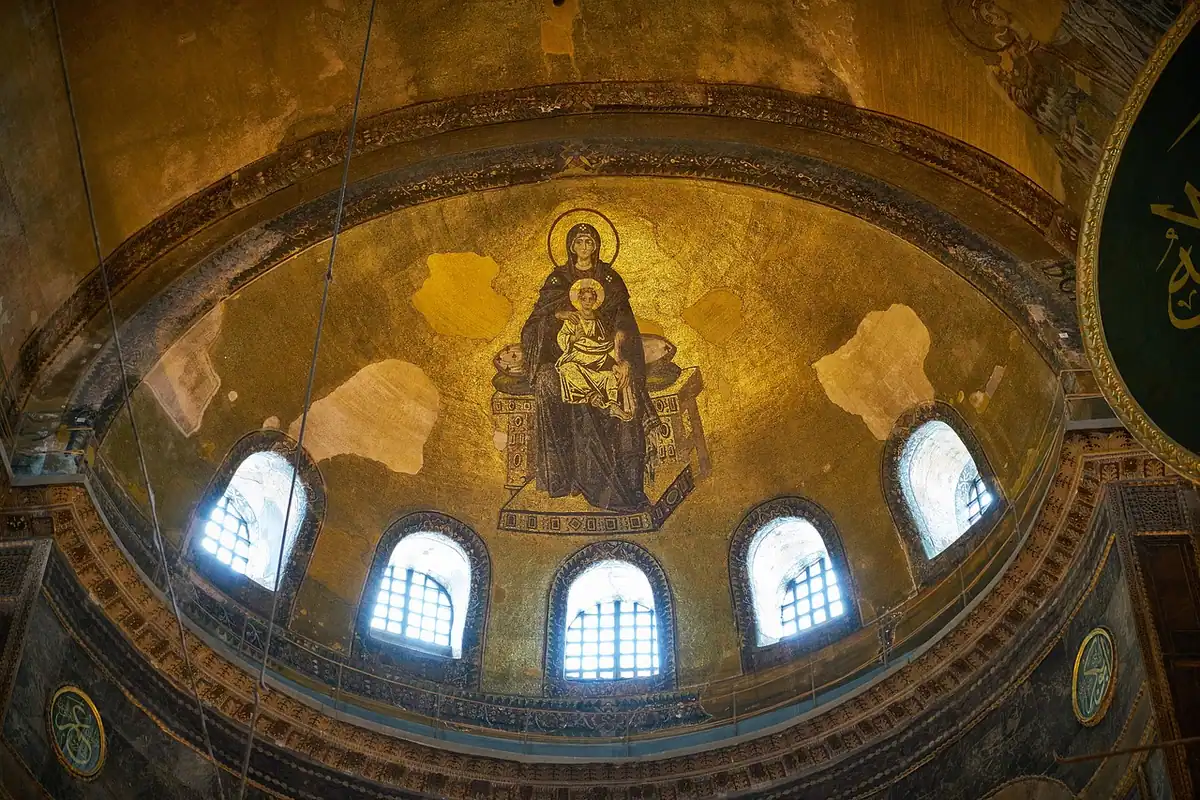 Interiorul unei vechi biserici cu cupolă mare, ferestre înalte și decor bogat în culori