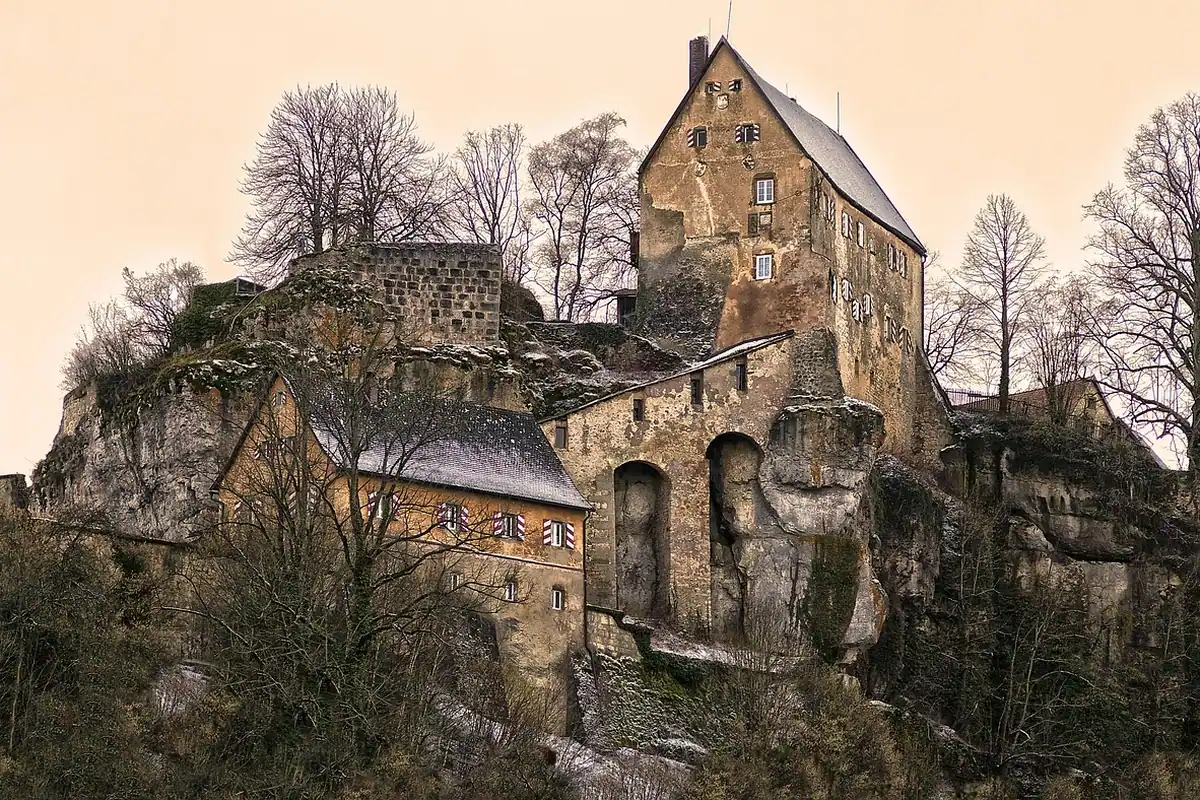 Ruinele unui castel medieval ridicat pe un vârf stâncos, cu ziduri impunătoare de piatră