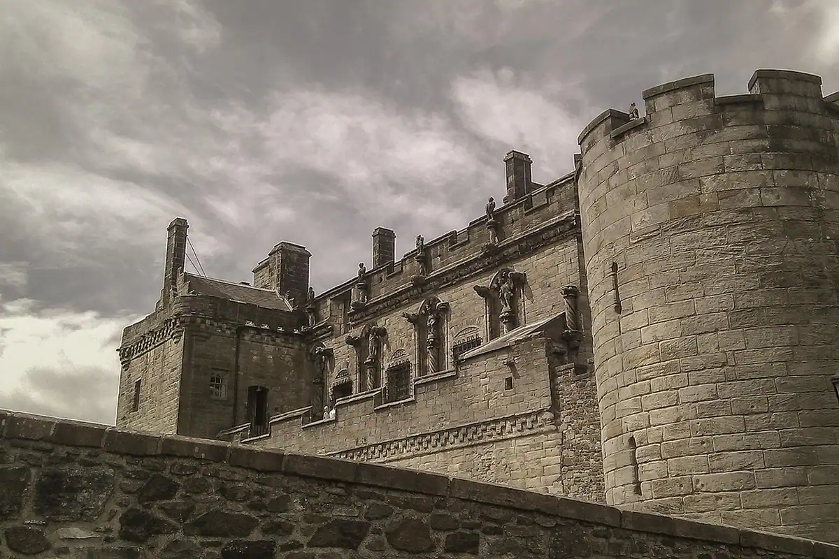 Castel de piatră cenușie cu ziduri înalte și creneluri, ridicat pe o înălțime