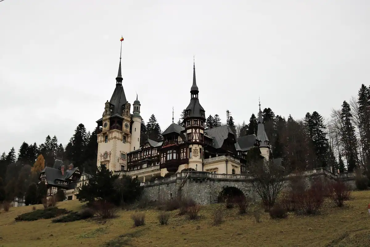 Castelul Peleș văzut de la distanță, cu pădurea și munții Bucegi în jur