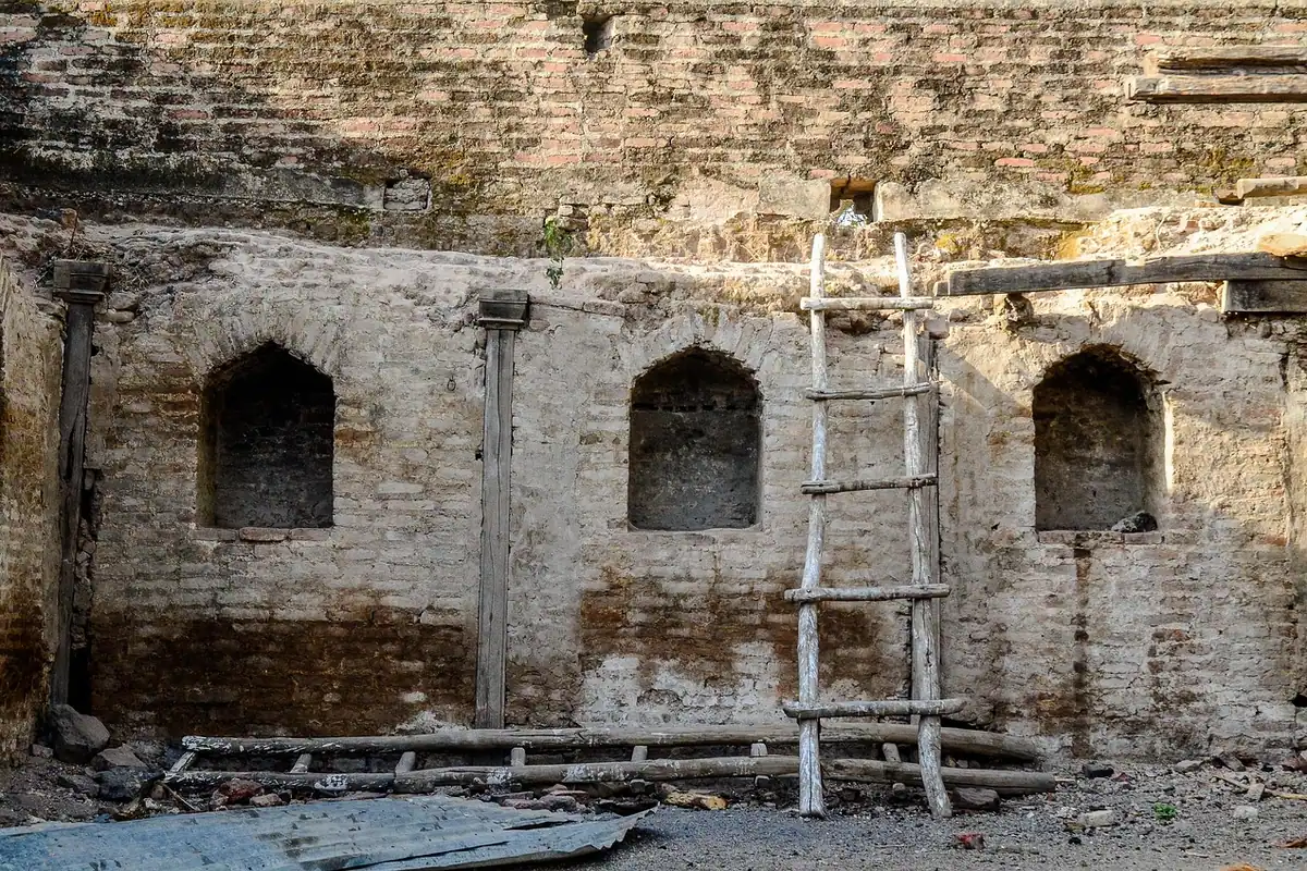 Scară sprijinită de un zid vechi și brut, într-un șantier de construcție sau restaurare