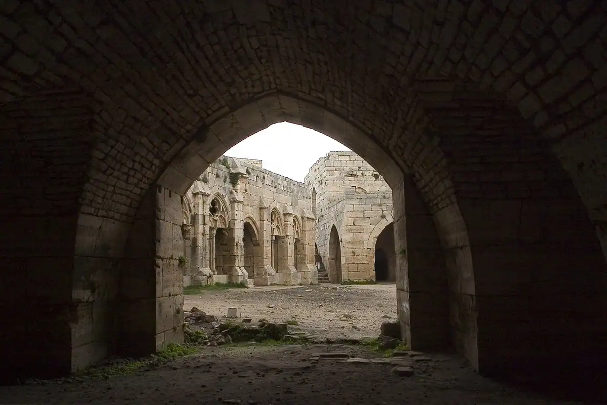 Ruine de cetate cruciată văzute printr-un arc de piatră întunecat