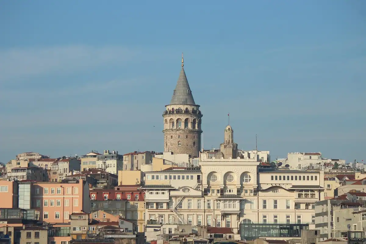 Turn istoric de piatră deasupra unui golf cu clădiri vechi, apă și cer senin
