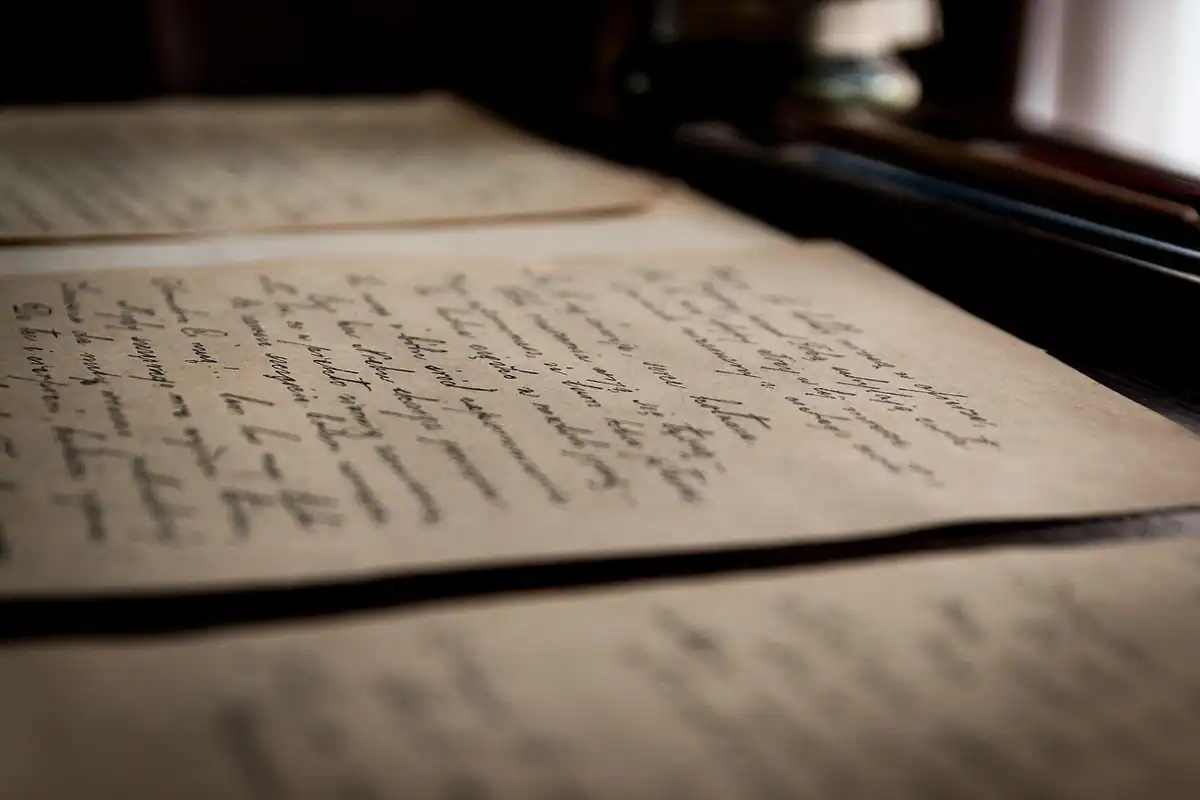 Litere vechi scrise de mână pe hârtie îngălbenită, document medieval