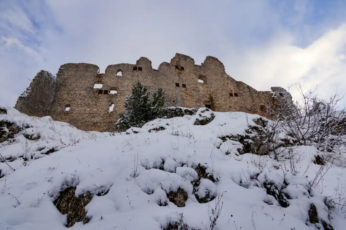 Ruine de cetate medievală acoperite de zăpadă, sub cerul de iarnă