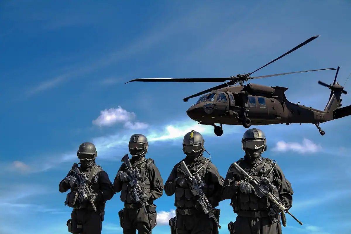 Soldați cu echipament militar și arme, lângă un elicopter, într-o acțiune de echipă
