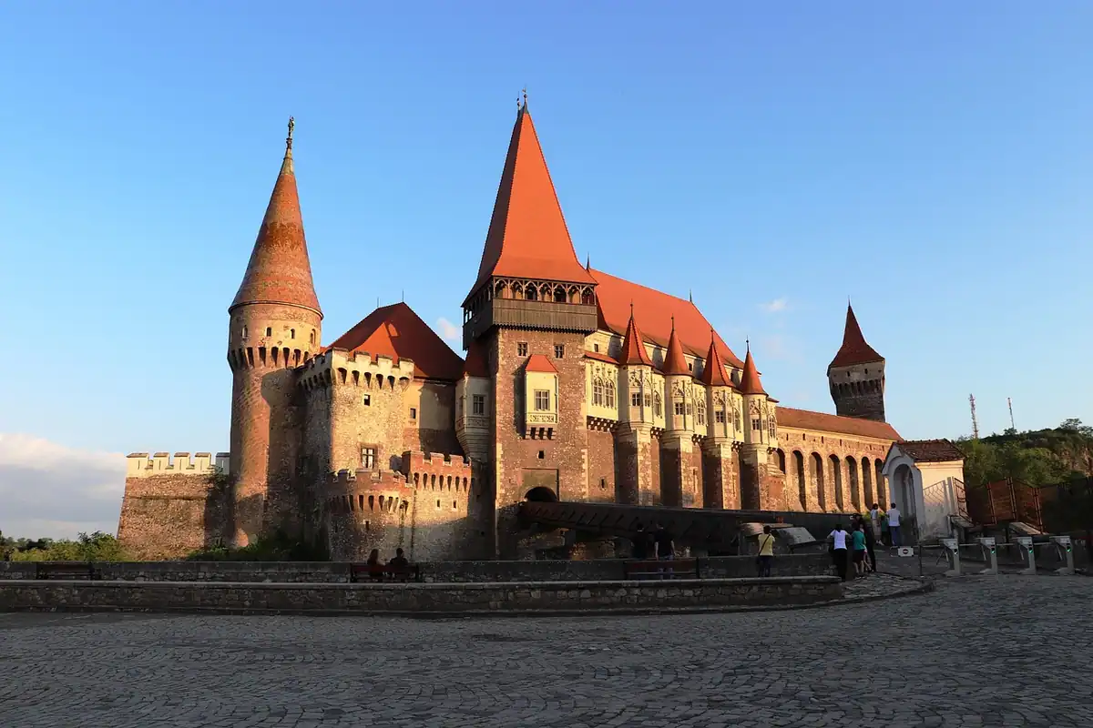 Castelul Corvinilor din Hunedoara la asfințit, cu acoperișuri ascuțite roșii