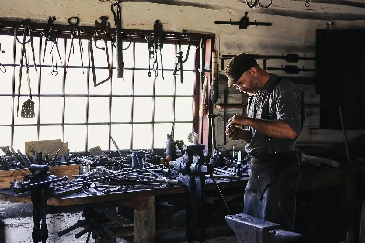 Atelier de meșteșugar cu unelte metalice, în care un om lucrează cu mâinile
