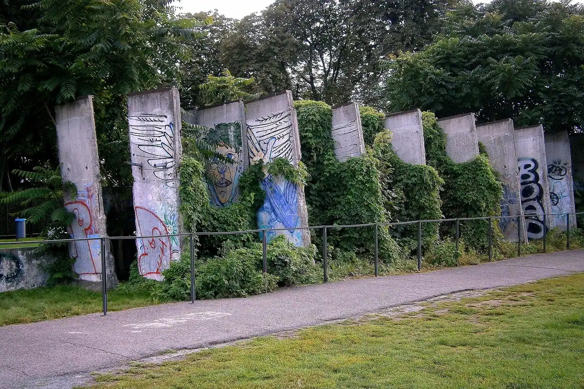 Fragmente din Zidul Berlinului, acoperite de graffiti și iederă, păstrate ca monument