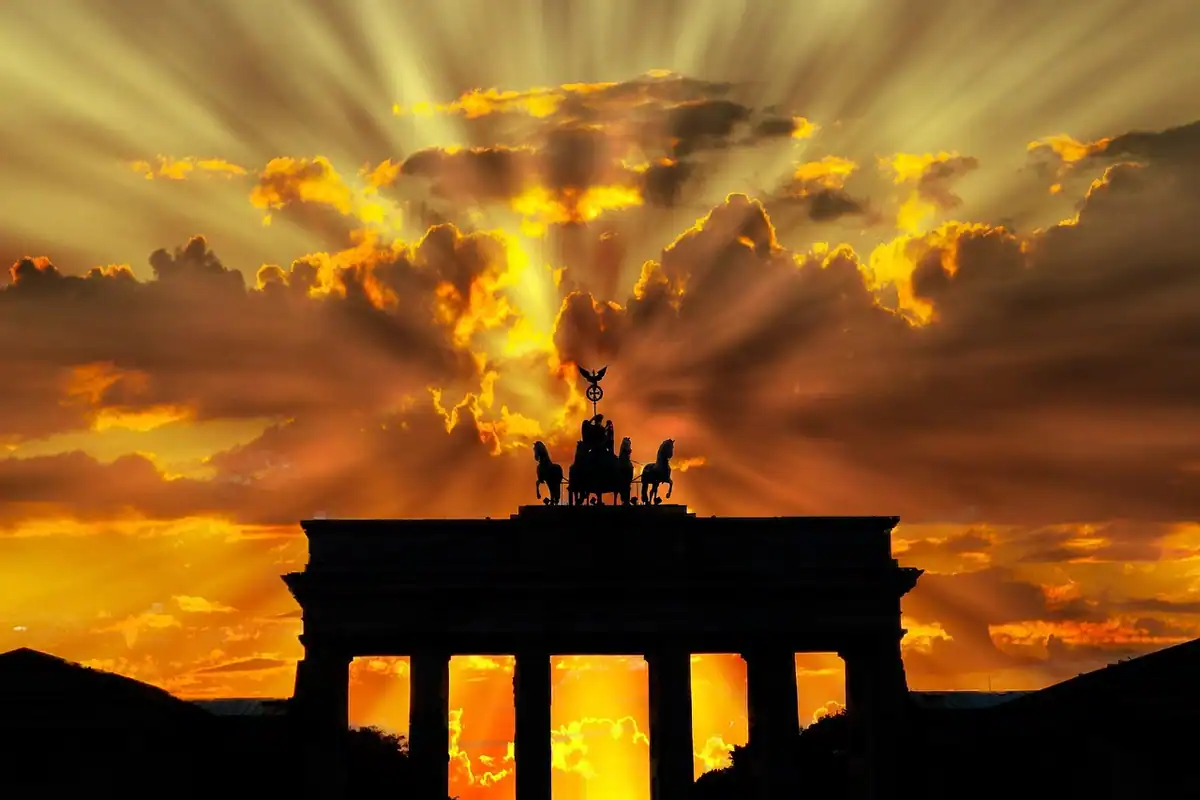 Poarta Brandenburg din Berlin, siluetă pe cer galben-portocaliu la apus