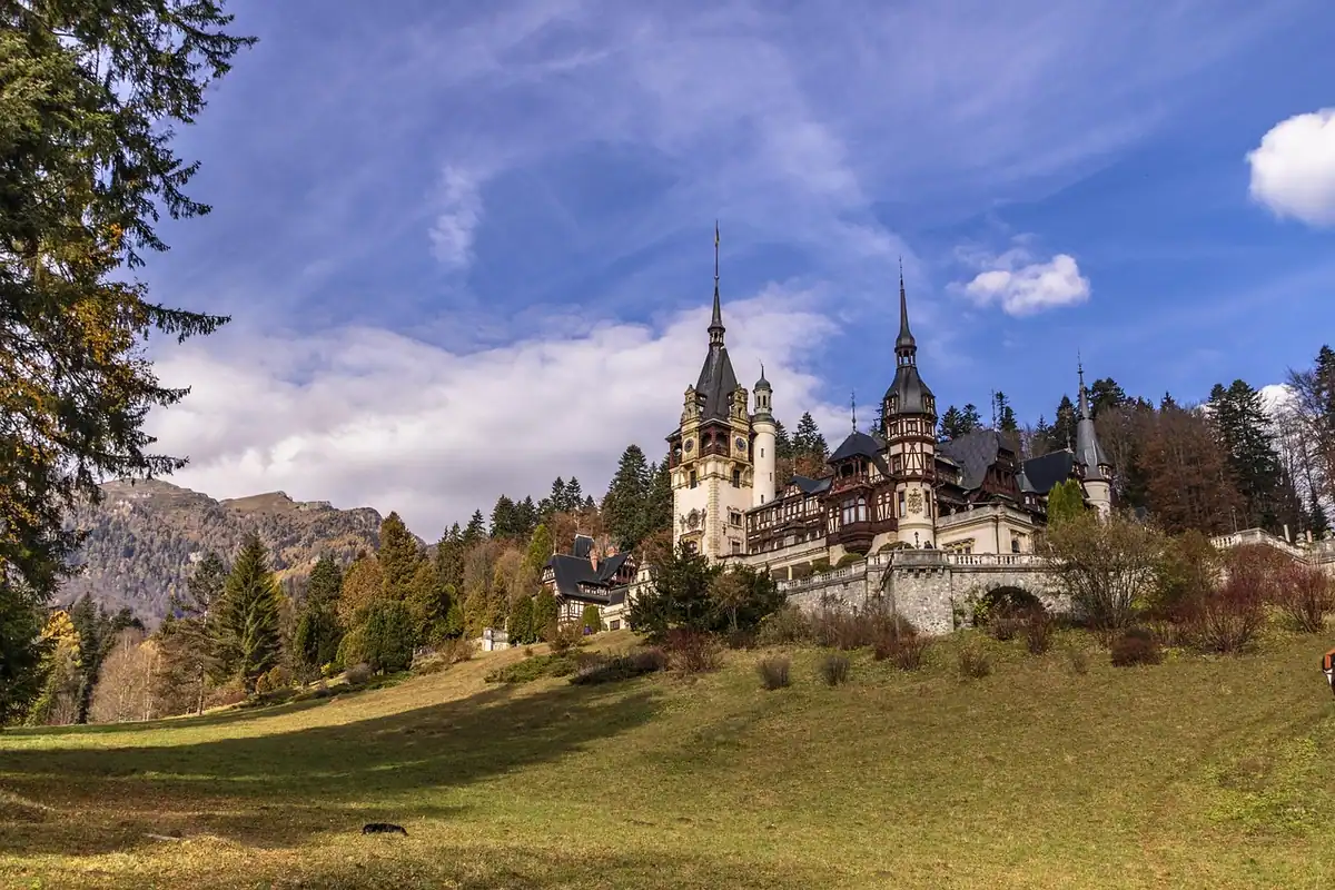 Castel vechi cu turnuri, înconjurat de natură și munți împăduriți