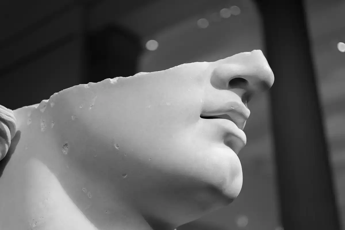 Cap de statuie din marmură, cu trăsături clasice, expus într-un muzeu