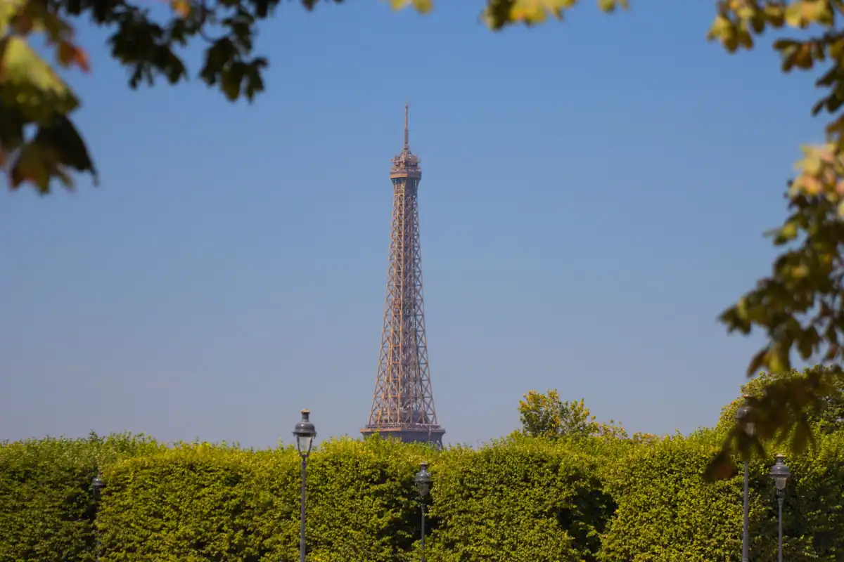 Turnul Eiffel privit peste o alee verde din Paris