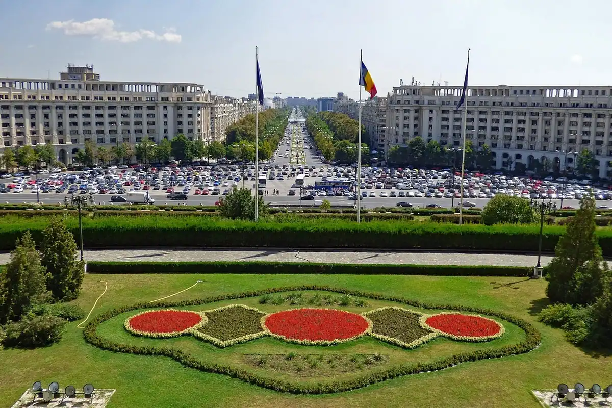 Palatul Parlamentului din București și drapelele tricolore, văzute de pe bulevard