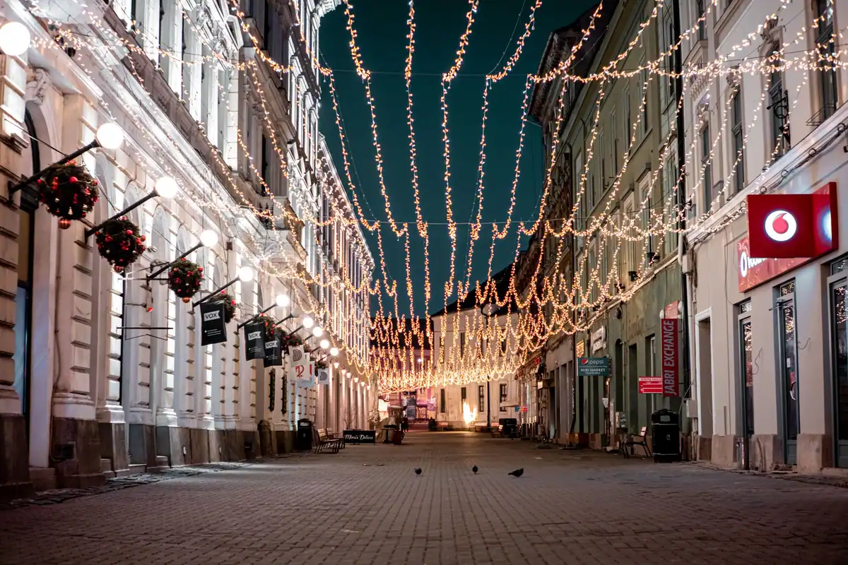 Stradă iluminată cu ghirlande, pe timp de seară, în Timișoara