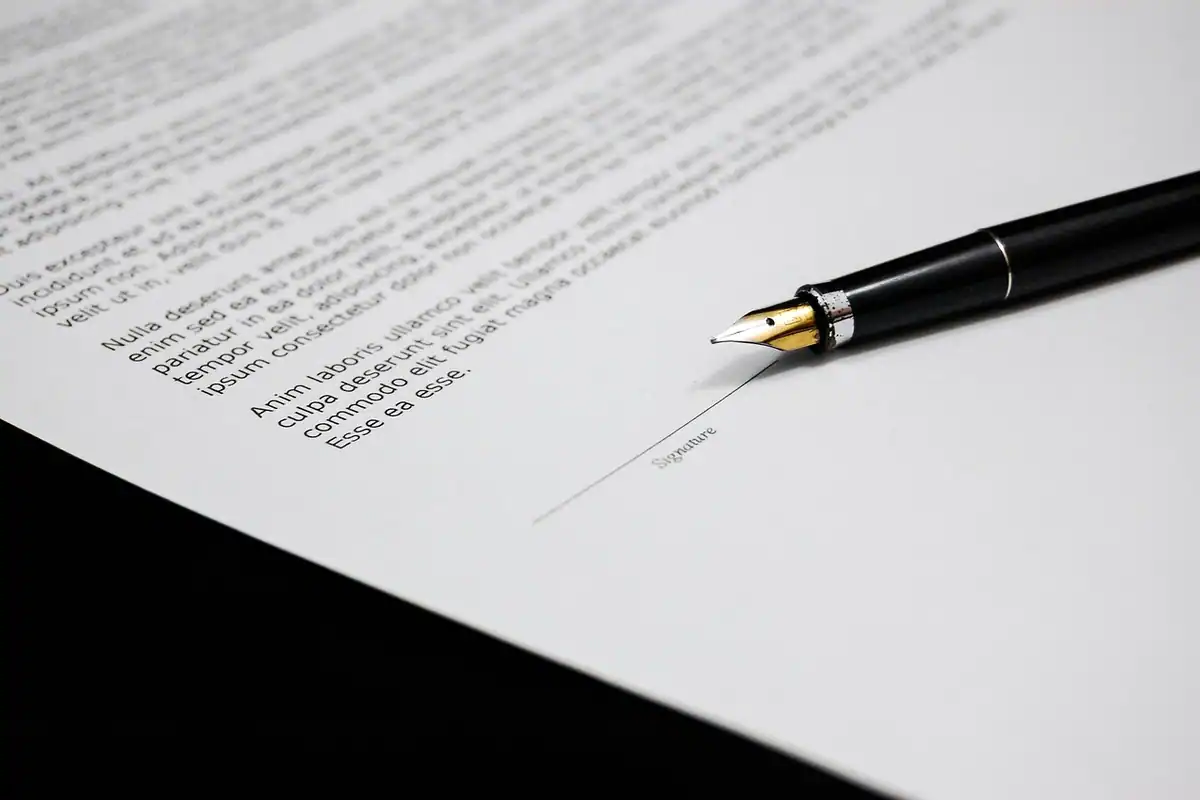 Document pe o masă, cu un stilou pus lângă semnătură, simbol al unui acord