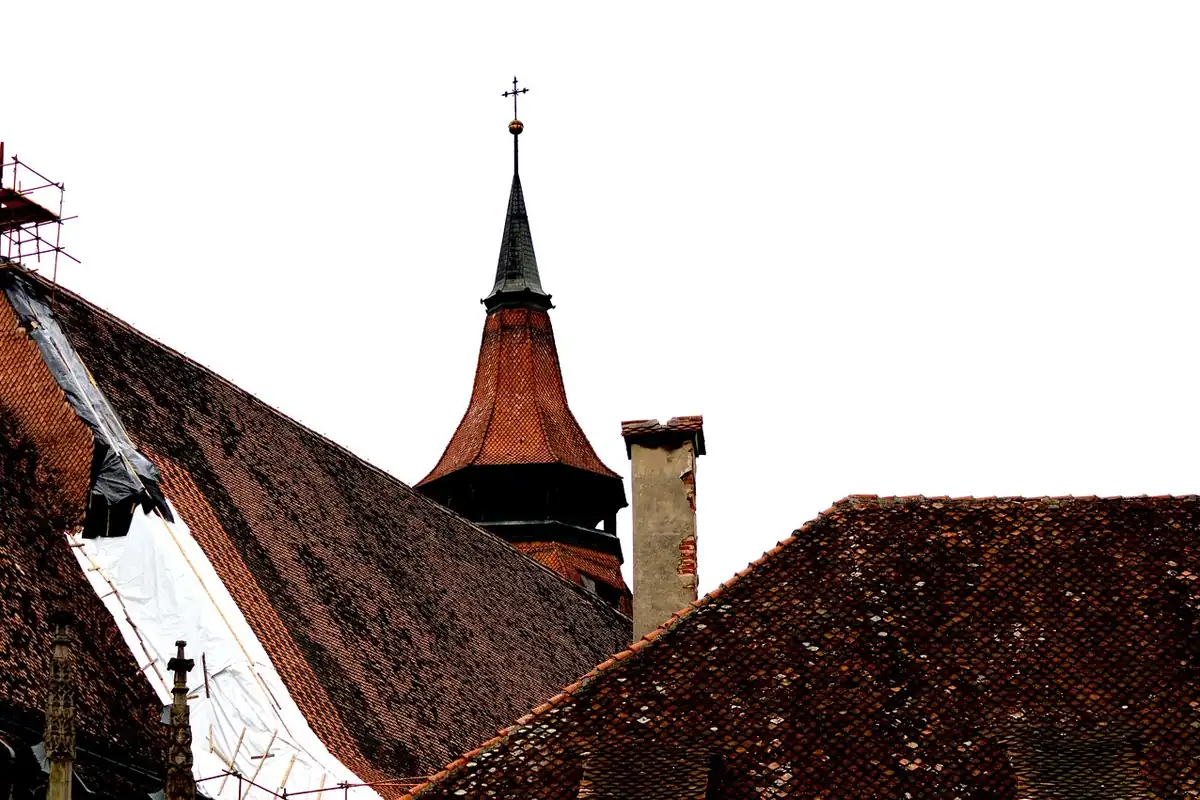 Acoperișuri vechi din țiglă și un turn cu cruce în Transilvania